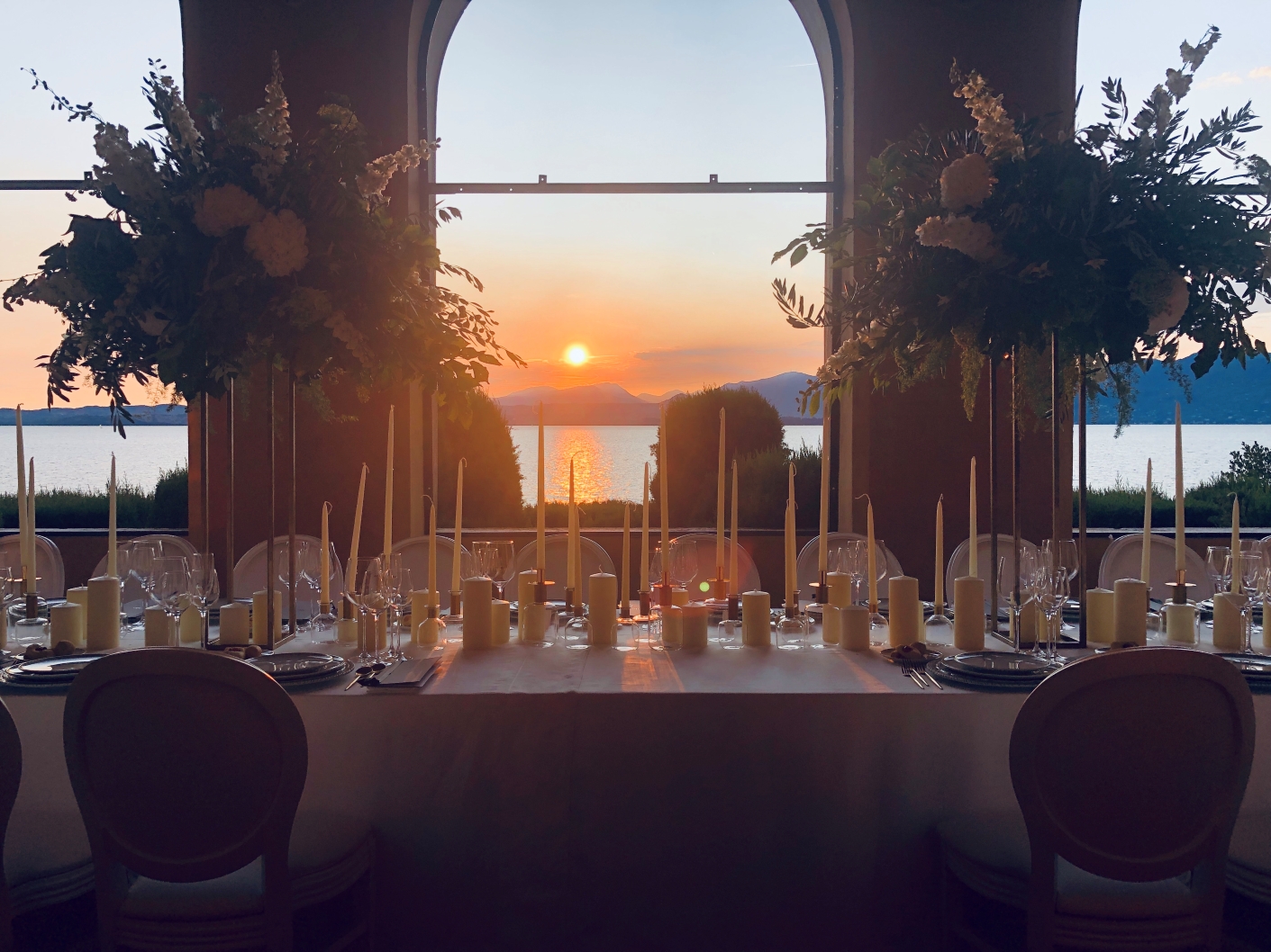 a table set with the sunset over the lake behind - ACCAELLE Events | Organizzazione eventi e Wedding planner