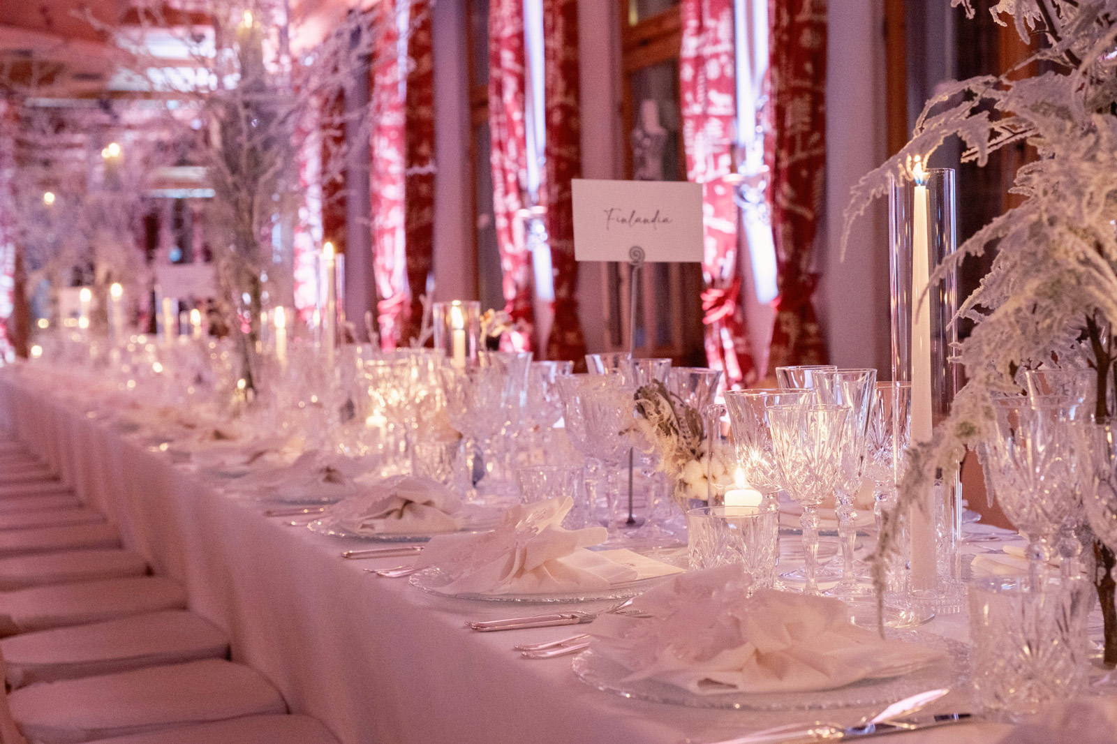 Elegant setting of a long table for a winter event, with a white tablecloth, crystals and snowy decorations - ACCAELLE Events | Organizzazione eventi e Wedding planner