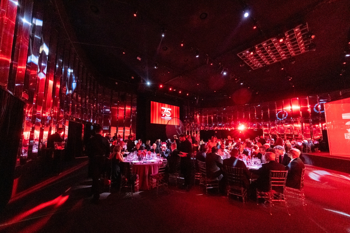 Large reception hall crowded with guests and bathed in warm red light. - ACCAELLE Events | Organizzazione eventi e Wedding planner