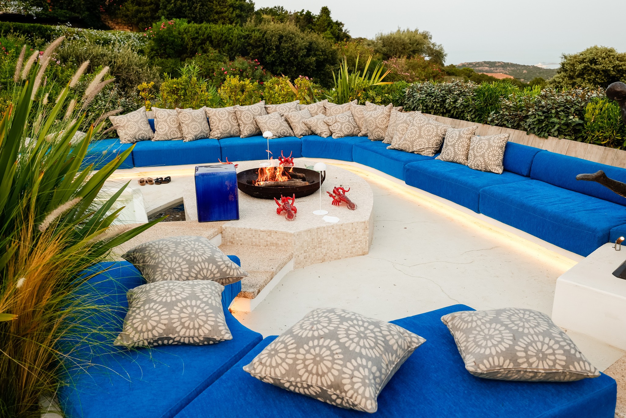 Poolside relaxation area with large blue sofas and cushions in a natural setting. - ACCAELLE Events | Organizzazione eventi e Wedding planner