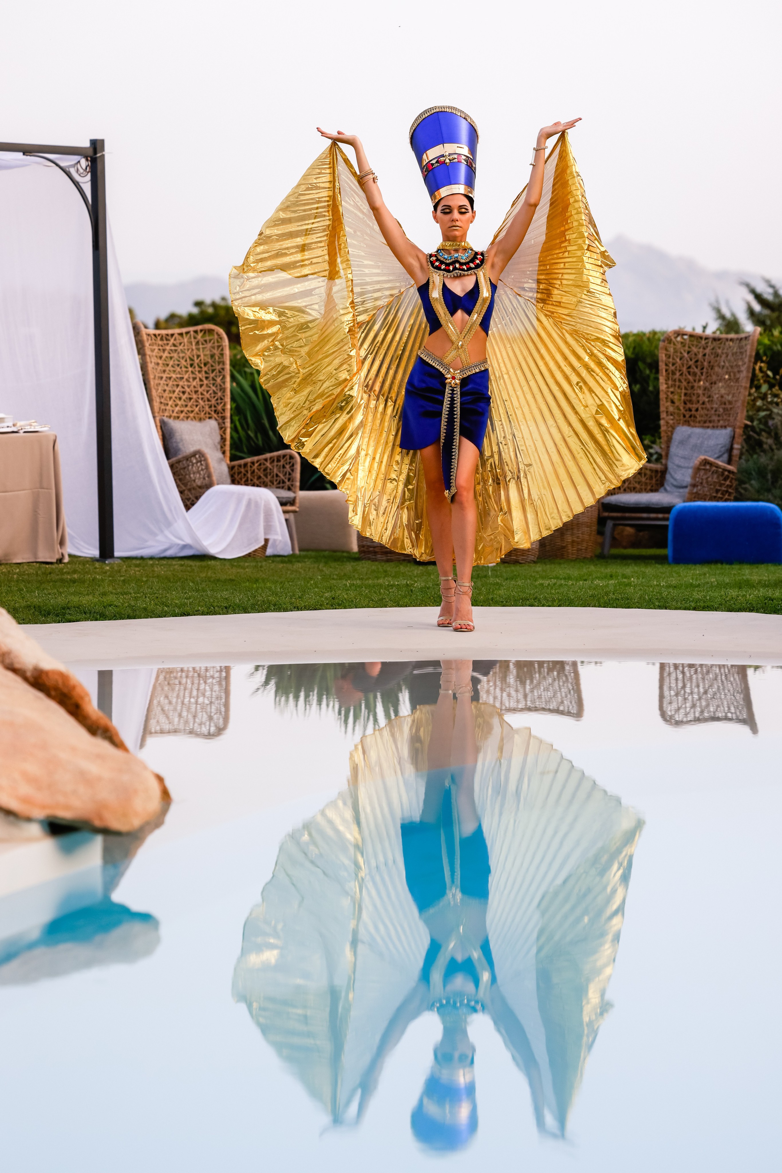 Artist in blue and gold costume dances by the pool with reflection in the water. - ACCAELLE Events | Organizzazione eventi e Wedding planner