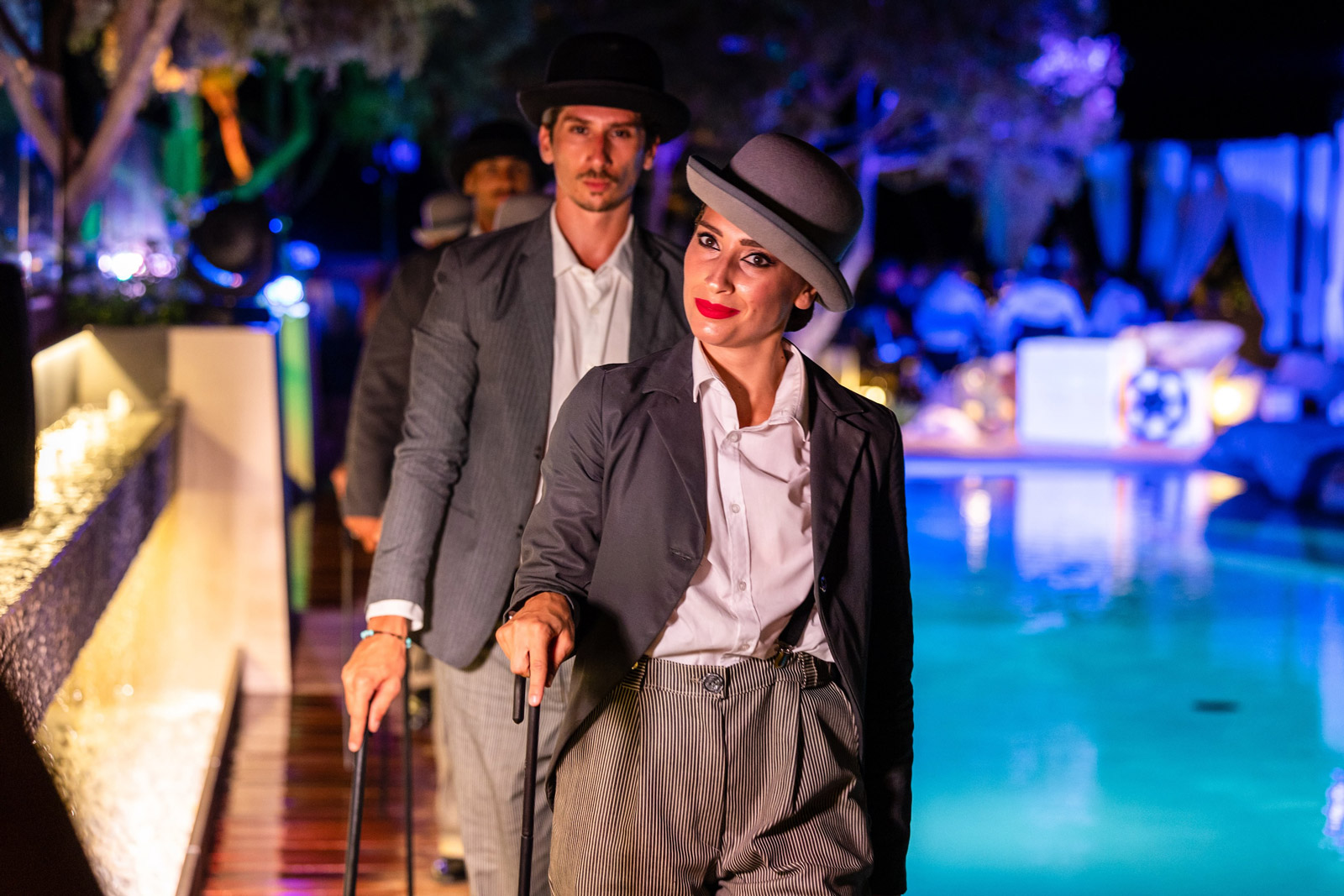 Actors in vintage period clothing and bowler hats pose near a swimming pool. - ACCAELLE Events | Organizzazione eventi e Wedding planner
