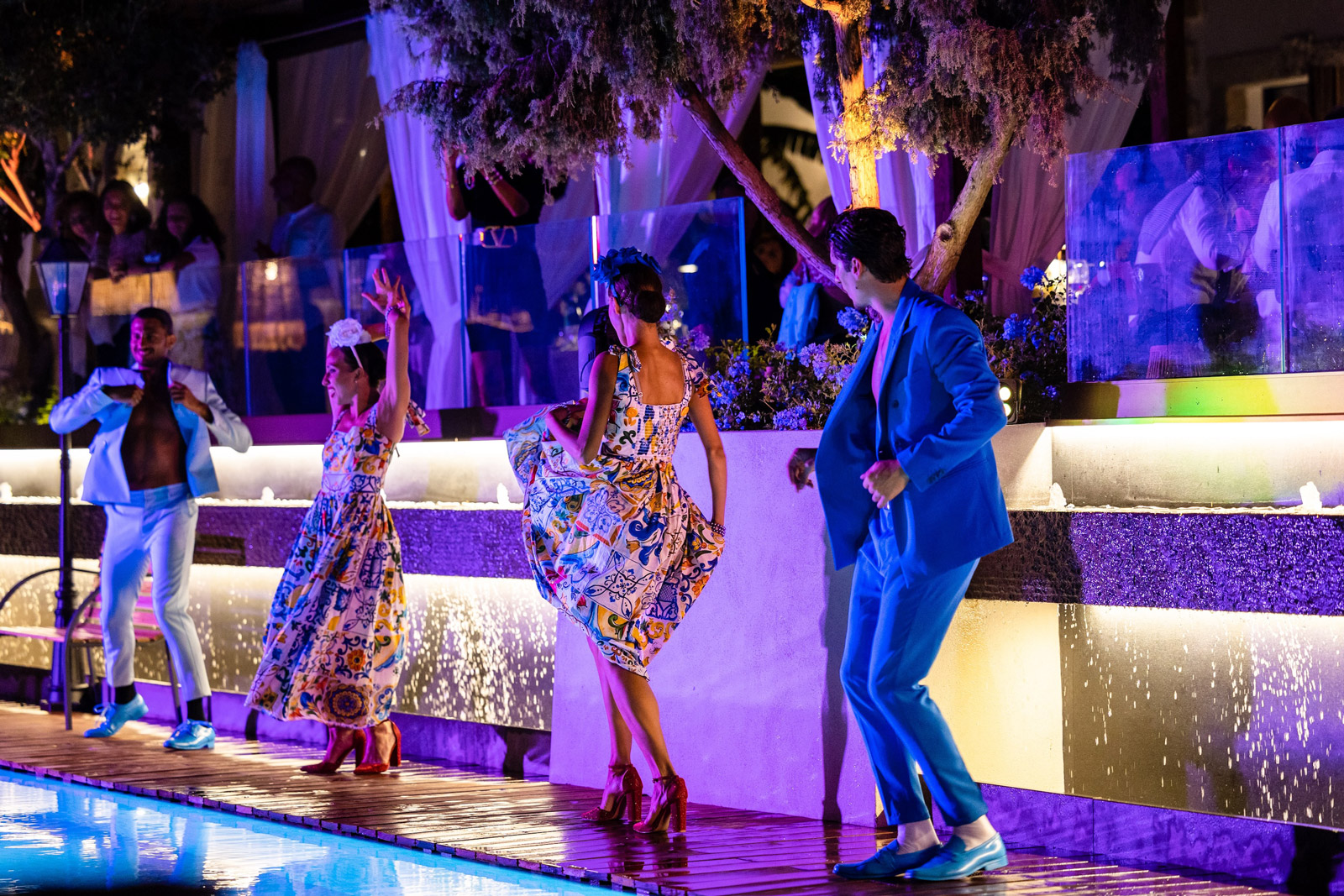 Dancers performing by the pool illuminated by a purple light in the evening - ACCAELLE Events | Organizzazione eventi e Wedding planner