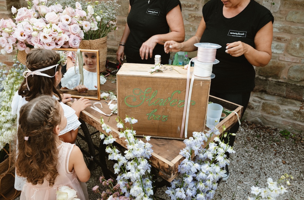 Little girls waiting to be served at a counter where they create floral bouquets - ACCAELLE Events | Organizzazione eventi e Wedding planner