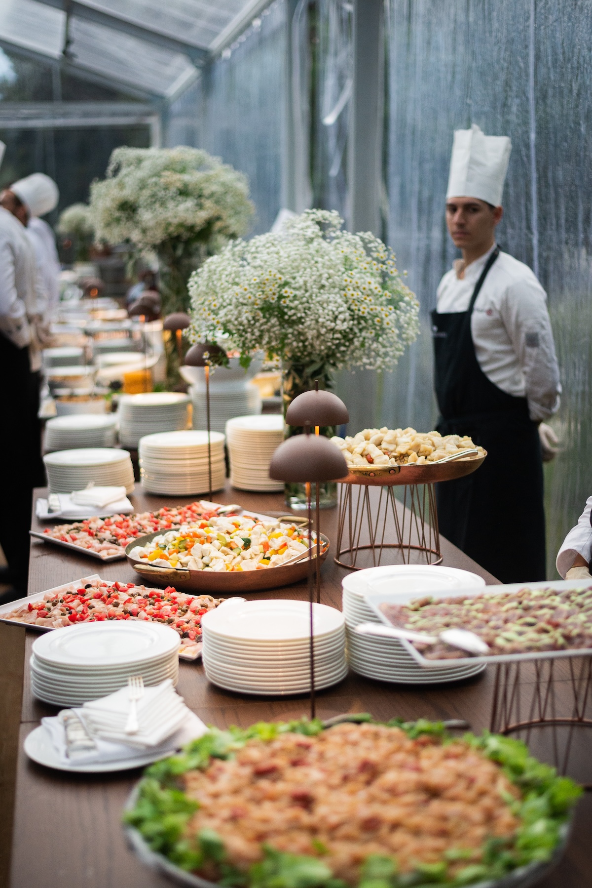 Professional chef in the kitchen preparing a rich buffet for events. - ACCAELLE Events | Organizzazione eventi e Wedding planner