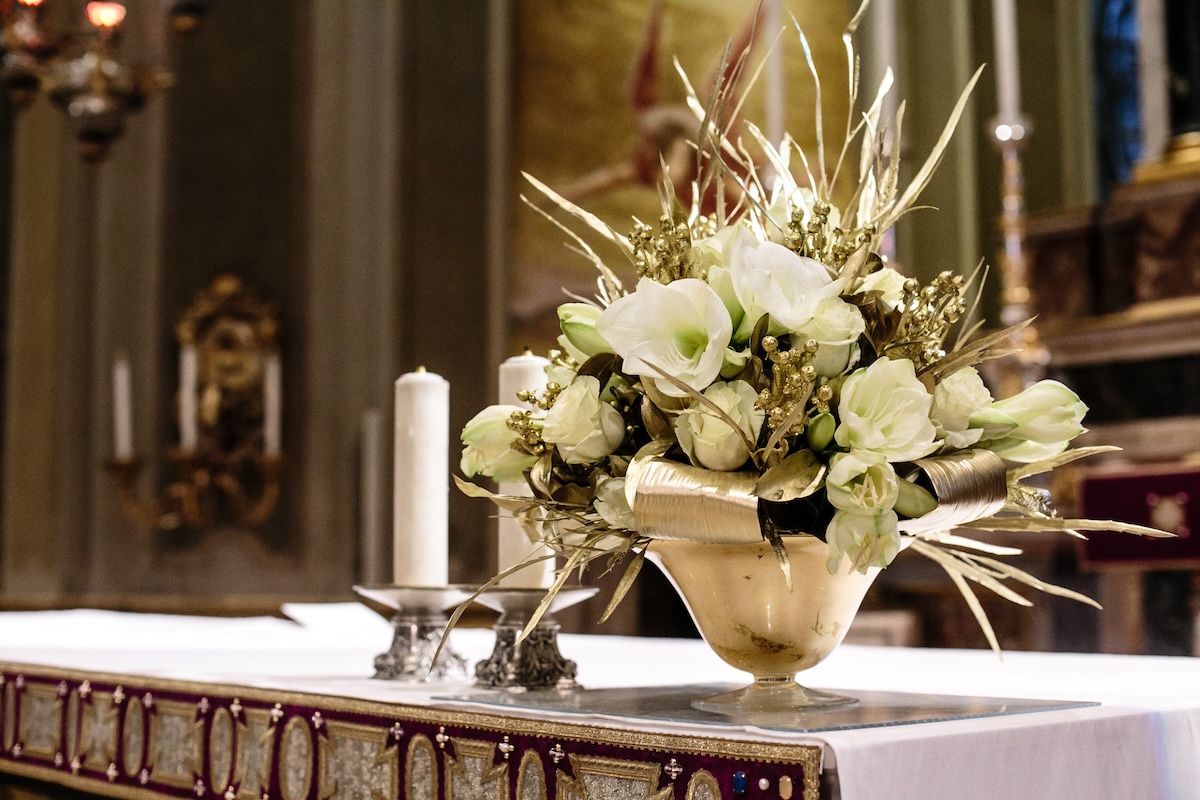 Artistic floral arrangement with white flowers and golden touches placed on the altar of a church for a wedding ceremony. - ACCAELLE Events | Organizzazione eventi e Wedding planner