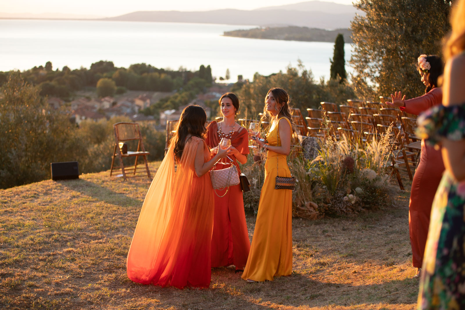 Bridesmaids in orange dresses in a garden with the sea in the background at night - ACCAELLE Events | Organizzazione eventi e Wedding planner