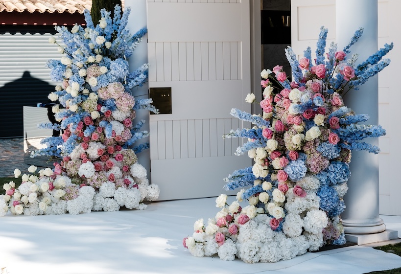 Multicolored floral decorations placed in front of a structure with white supporting columns - ACCAELLE Events | Organizzazione eventi e Wedding planner