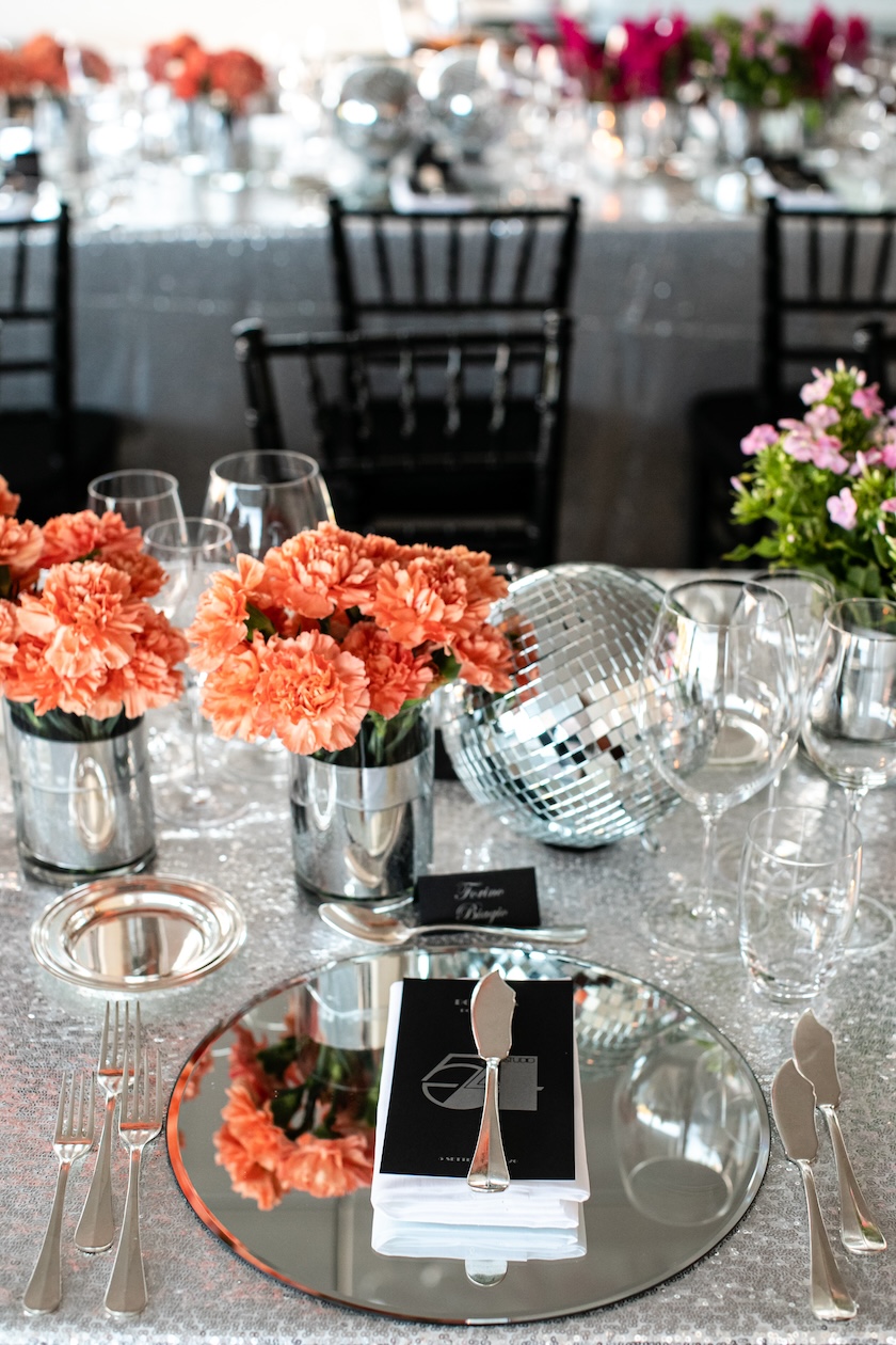 Detail of the table setting with an orange flower centerpiece and a dark menu. - ACCAELLE Events | Organizzazione eventi e Wedding planner