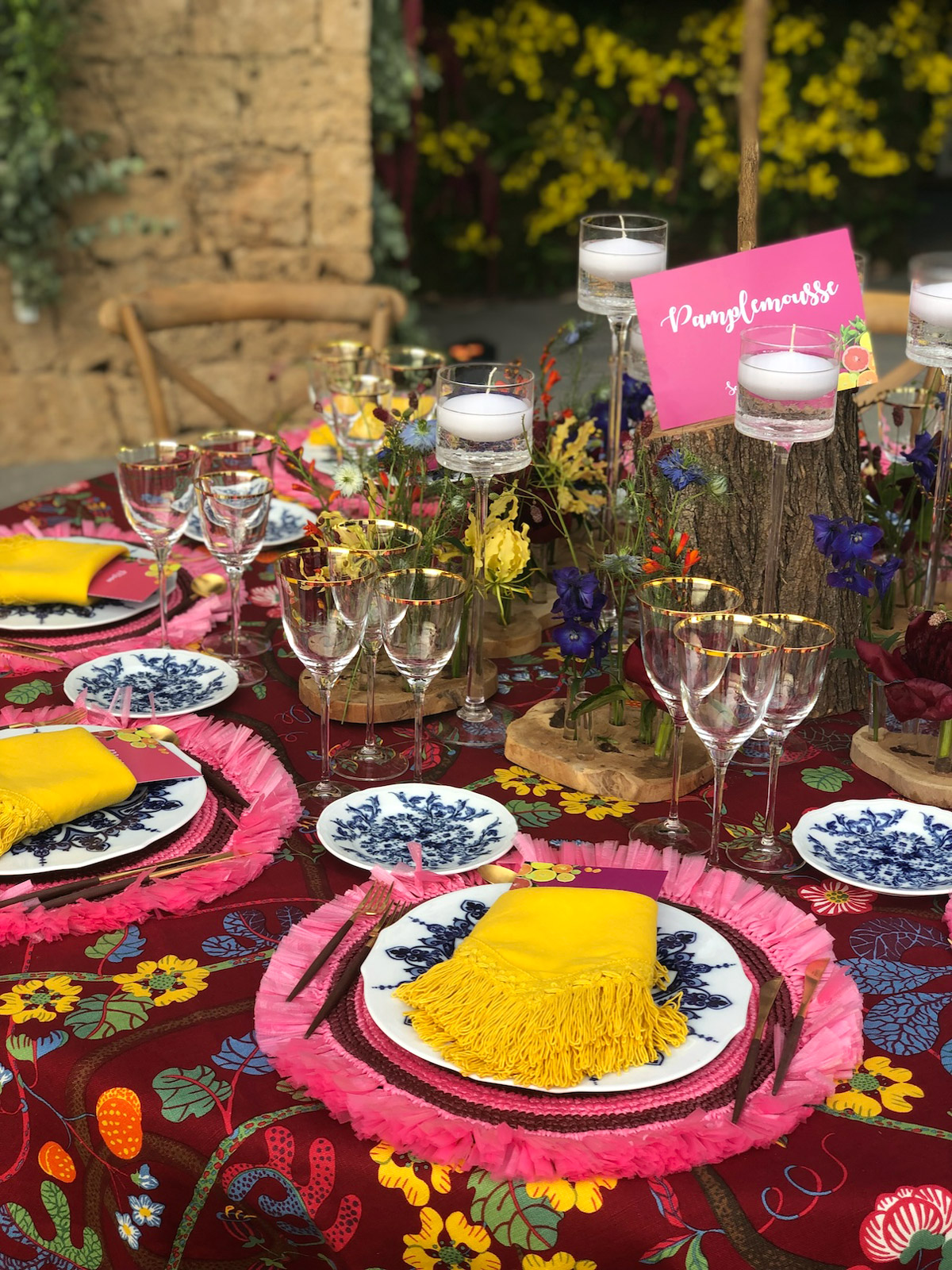 Detail of the lively table setting with colorful plates and pink place cards on ethnic fabric - ACCAELLE Events | Organizzazione eventi e Wedding planner