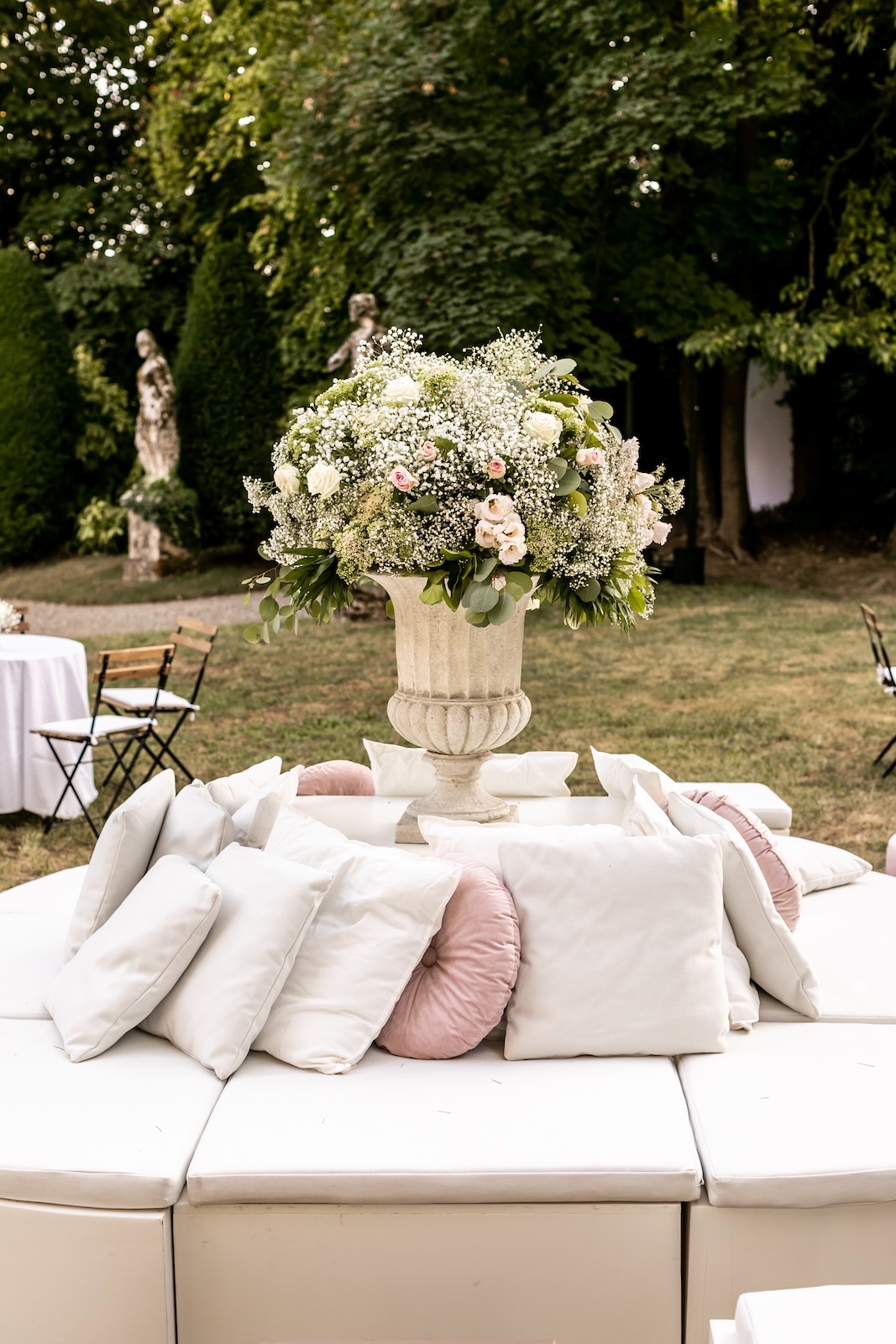 Detail of a circular lounge chair with cushions and an elegant floral centerpiece. - ACCAELLE Events | Organizzazione eventi e Wedding planner