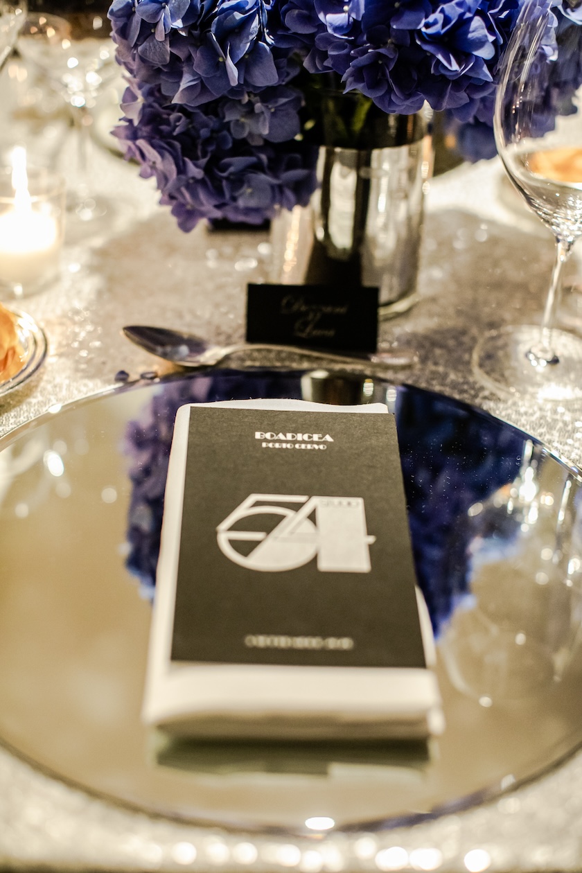 Close-up detail of the mise en place with a dark menu placed on a mirrored placemat. - ACCAELLE Events | Organizzazione eventi e Wedding planner
