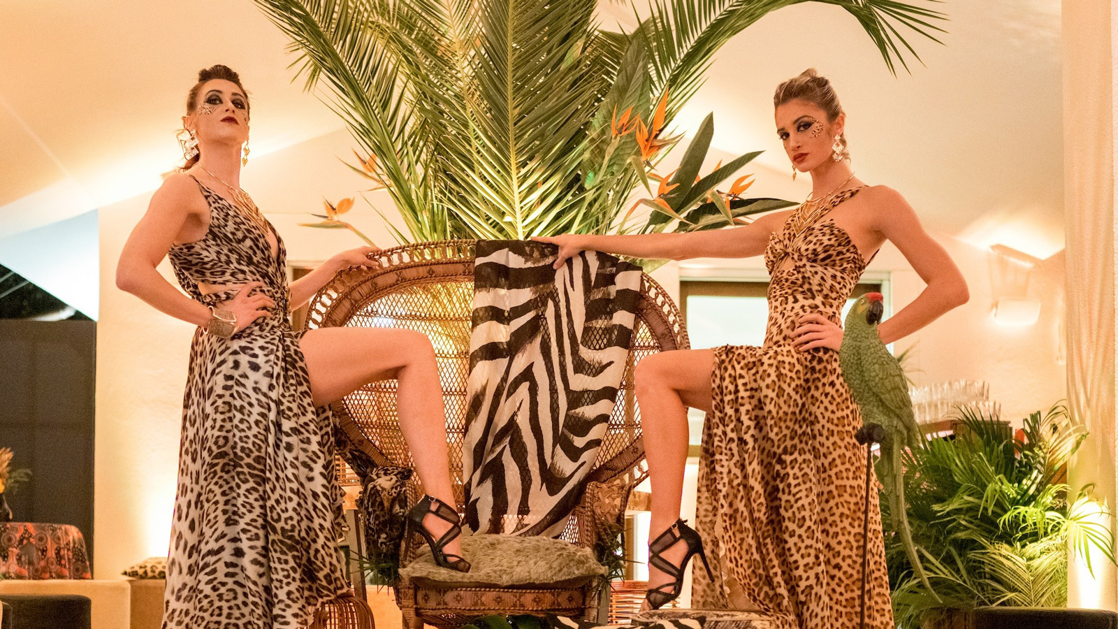Two models in leopard-print dresses pose next to a wicker chair with zebra details. - ACCAELLE Events | Organizzazione eventi e Wedding planner