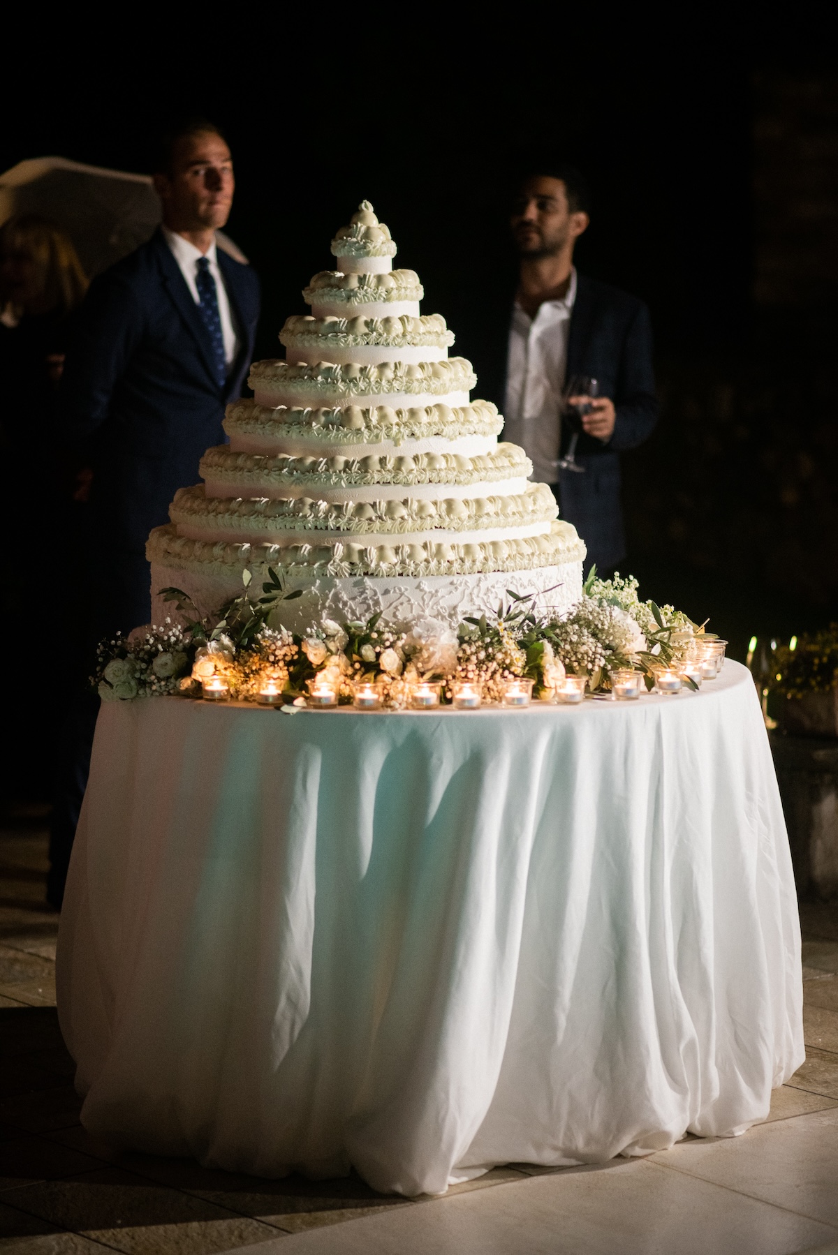 Elegant tiered wedding cake on a table with a white tablecloth and bright floral decorations. - ACCAELLE Events | Organizzazione eventi e Wedding planner