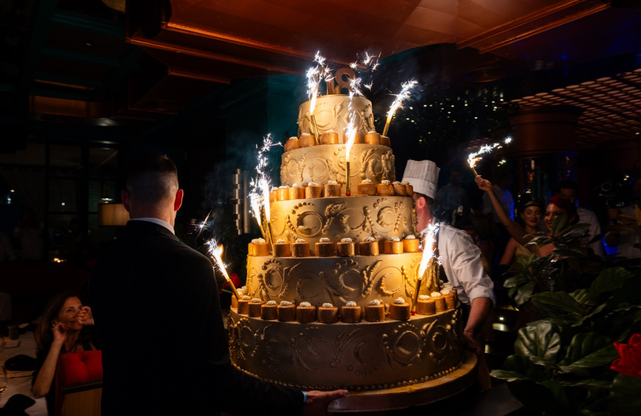 Large tiered wedding cake illuminated by light fountains during an event. - ACCAELLE Events | Organizzazione eventi e Wedding planner