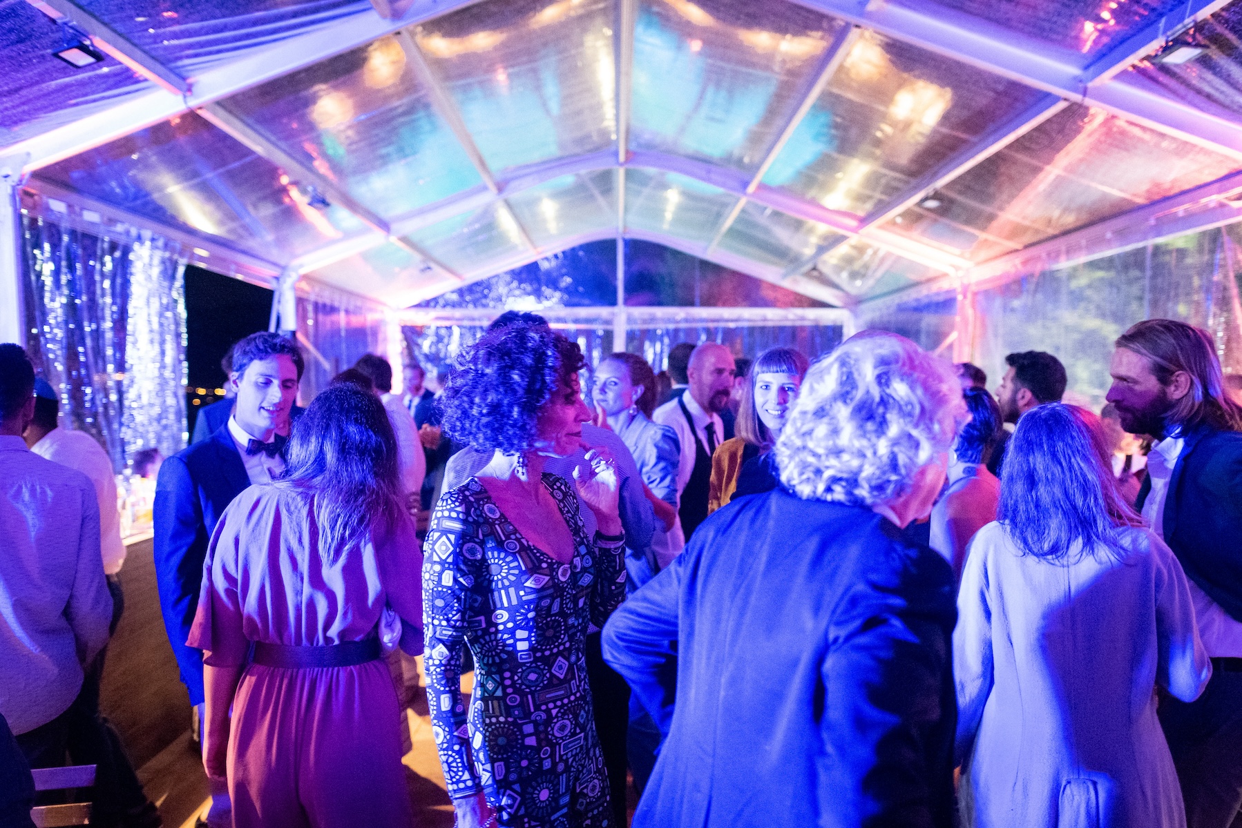 Group of guests dancing under a lit structure during an evening event. - ACCAELLE Events | Organizzazione eventi e Wedding planner