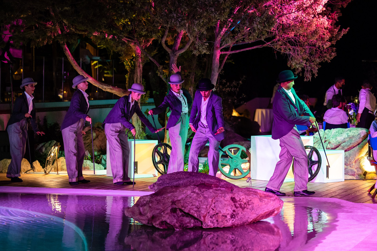 Group of performers in jackets performing by the pool under purple lights. - ACCAELLE Events | Organizzazione eventi e Wedding planner
