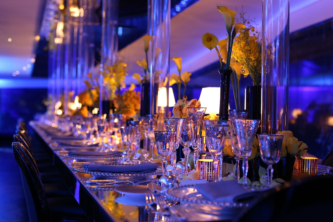 Long elegant table with yellow floral decorations and lighting in an evening setting - ACCAELLE Events | Organizzazione eventi e Wedding planner