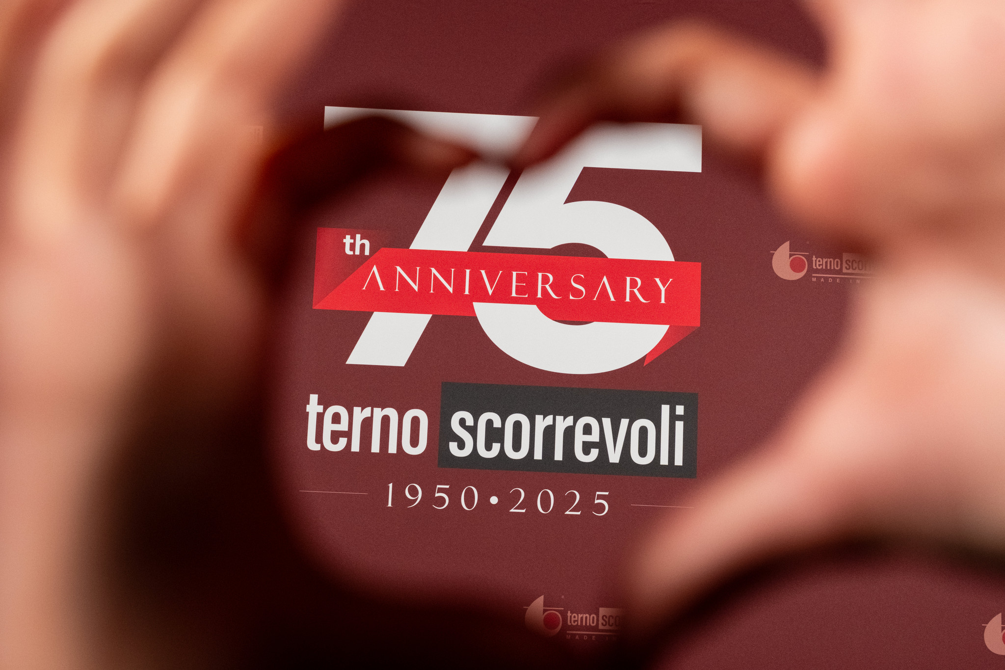 Hands forming a heart around the 75th anniversary logo of Terno Sliding - ACCAELLE Events | Organizzazione eventi e Wedding planner