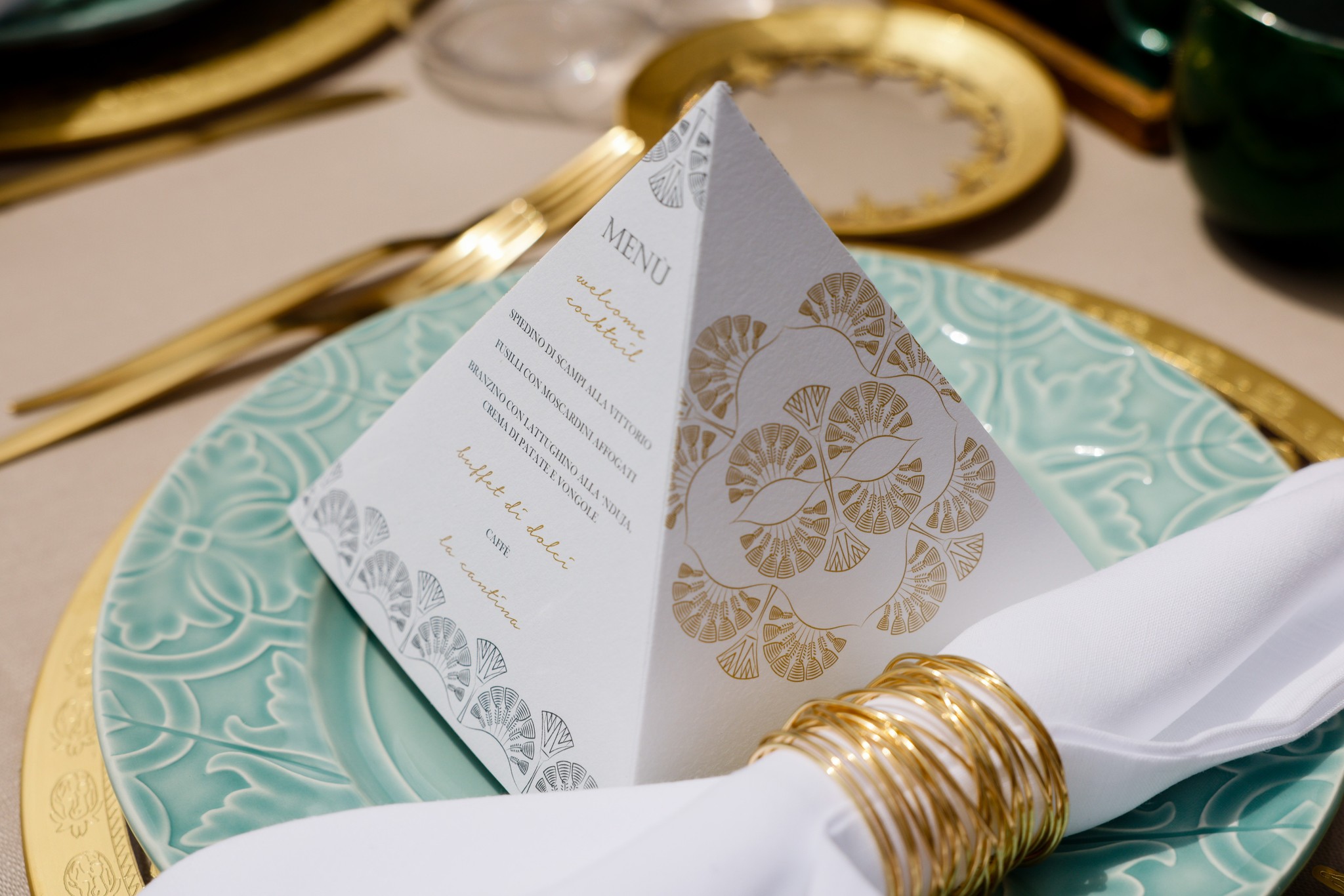 Pyramid-shaped menu with gold decorations on a finely decorated plate. - ACCAELLE Events | Organizzazione eventi e Wedding planner