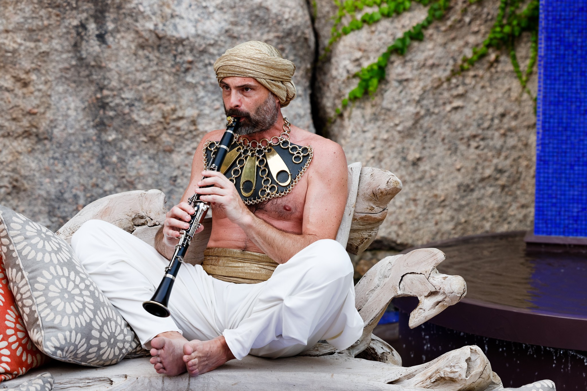 Musician sitting on cushions plays the clarinet wearing traditional clothing and themed accessories. - ACCAELLE Events | Organizzazione eventi e Wedding planner