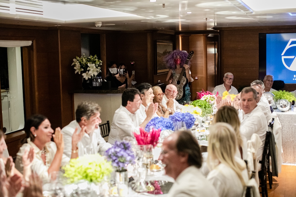 Guests sitting at a long table inside a yacht - ACCAELLE Events | Organizzazione eventi e Wedding planner
