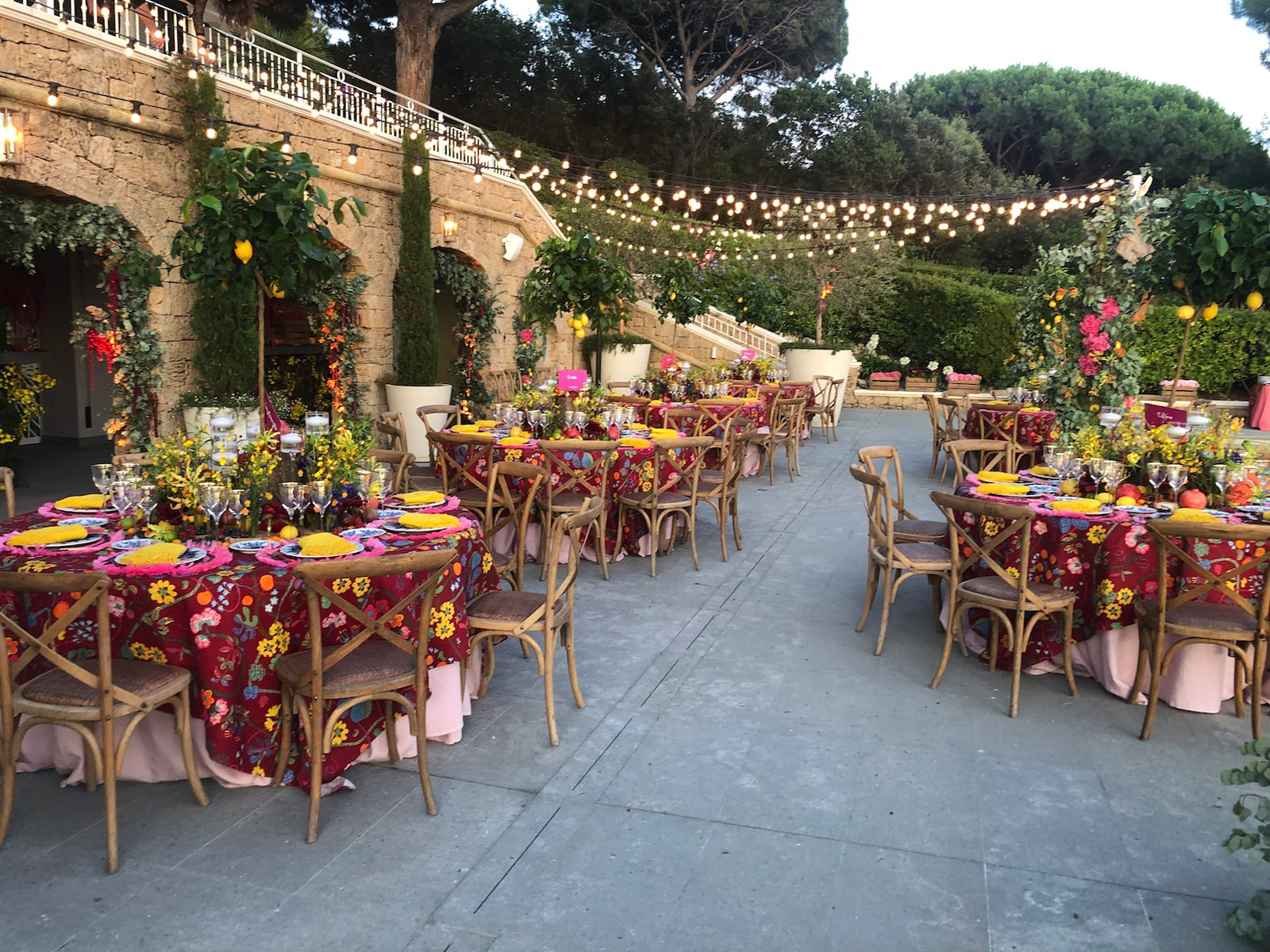Overview of an outdoor courtyard set up with numerous round tables for a festive reception - ACCAELLE Events | Organizzazione eventi e Wedding planner