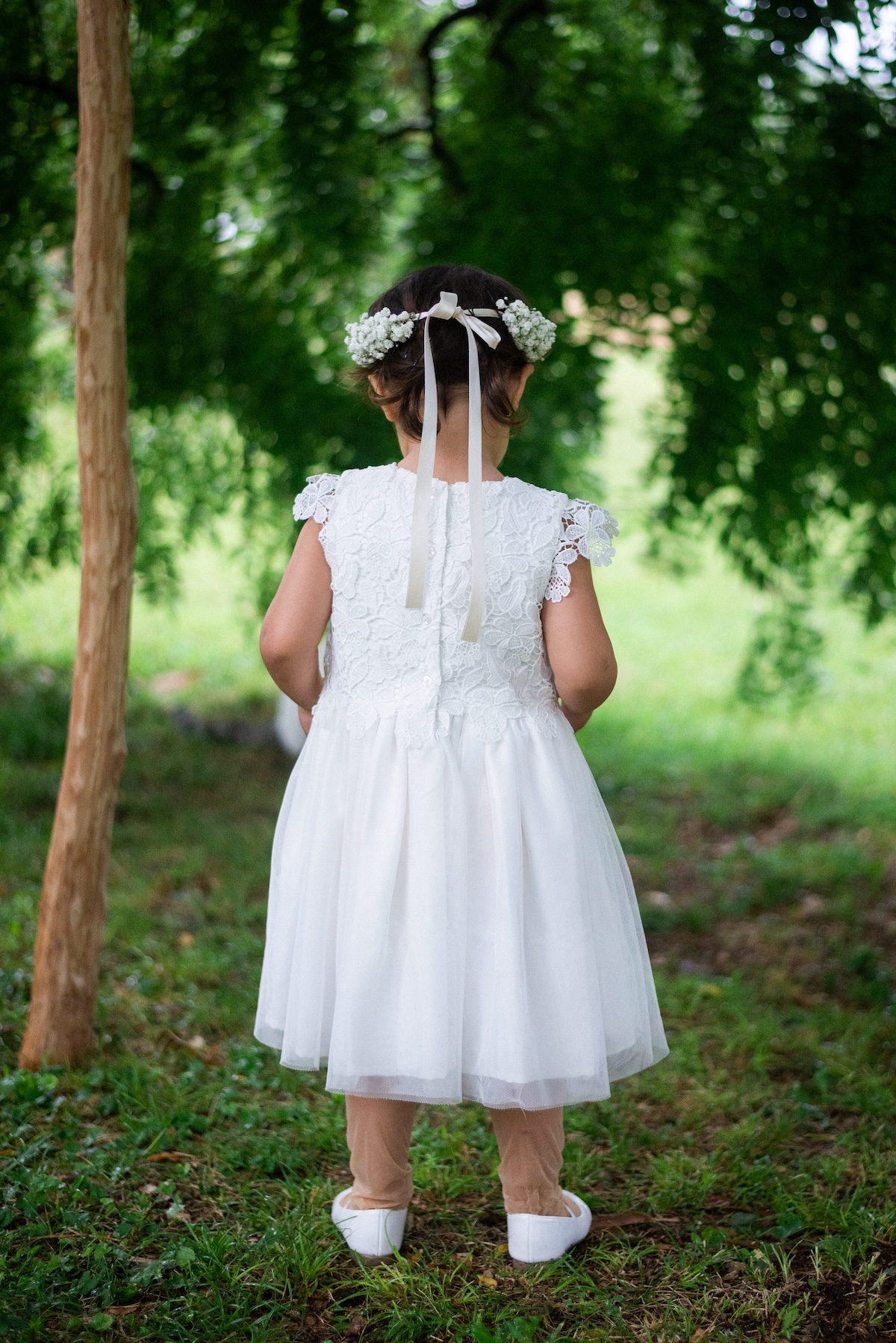 Little bridesmaid in white dress and floral crown in a garden - ACCAELLE Events | Organizzazione eventi e Wedding planner