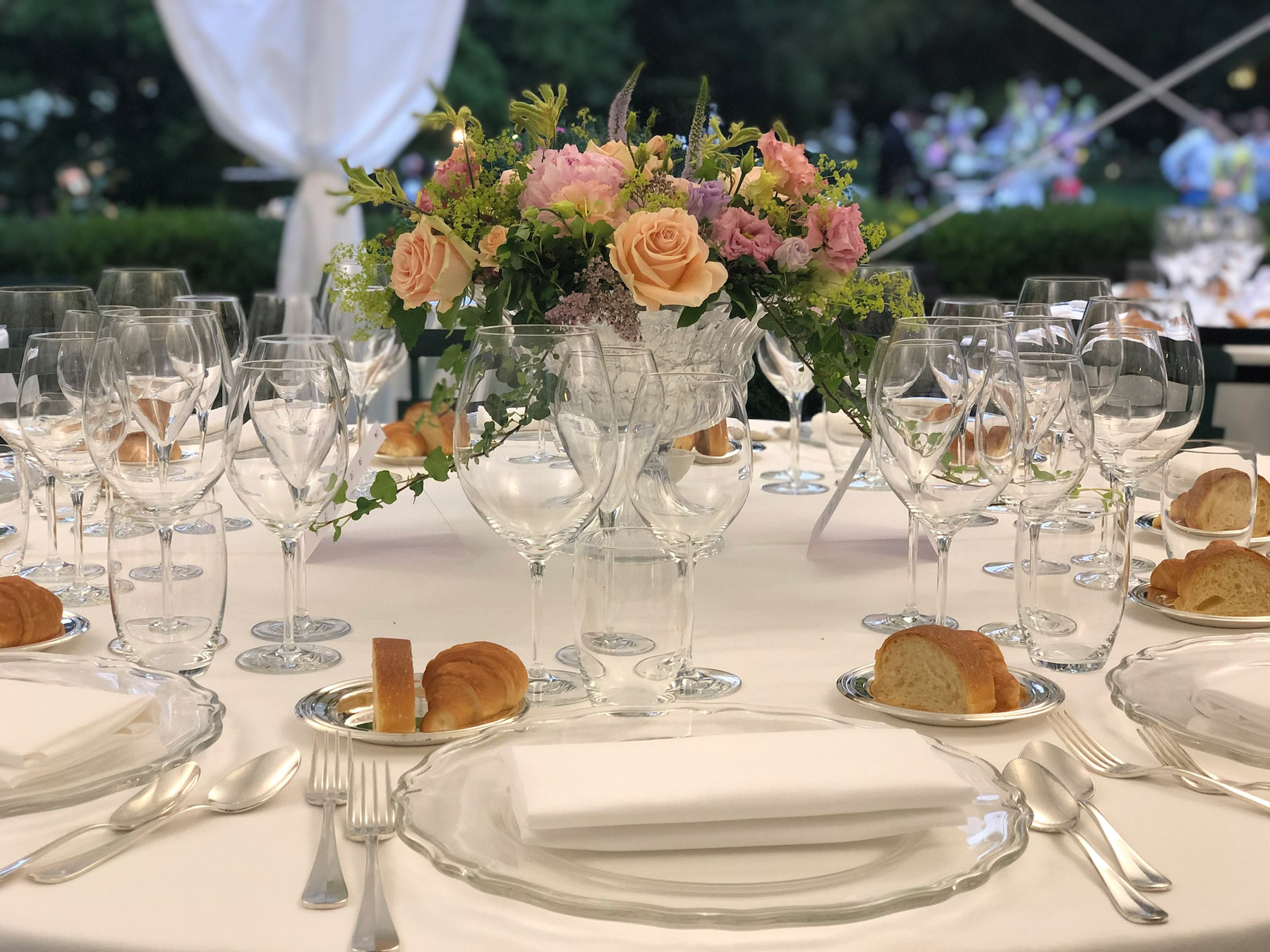 Close-up of a dinner table setting with a basket of flowers in the center. - ACCAELLE Events | Organizzazione eventi e Wedding planner