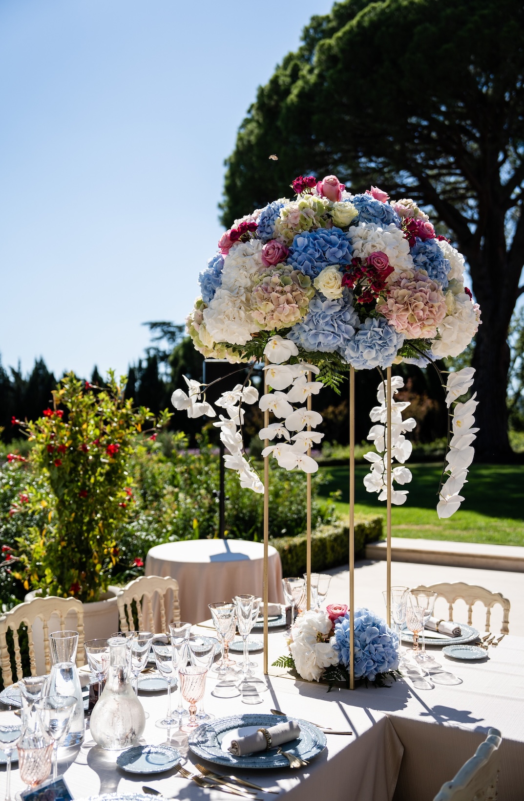 Close-up of a bouquet of multicolored flowers on a wedding lunch table with green lawn and trees in the background - ACCAELLE Events | Organizzazione eventi e Wedding planner