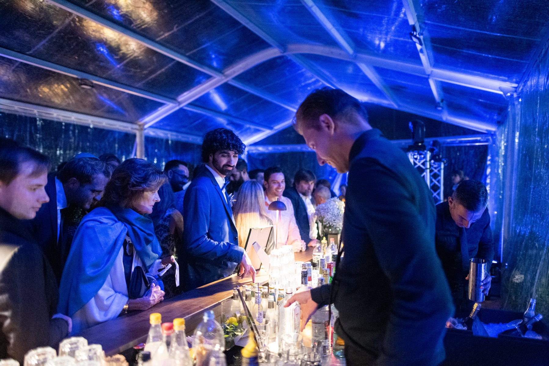 Close-up of waiters serving guests during an event in a greenhouse illuminated by blue lights - ACCAELLE Events | Organizzazione eventi e Wedding planner