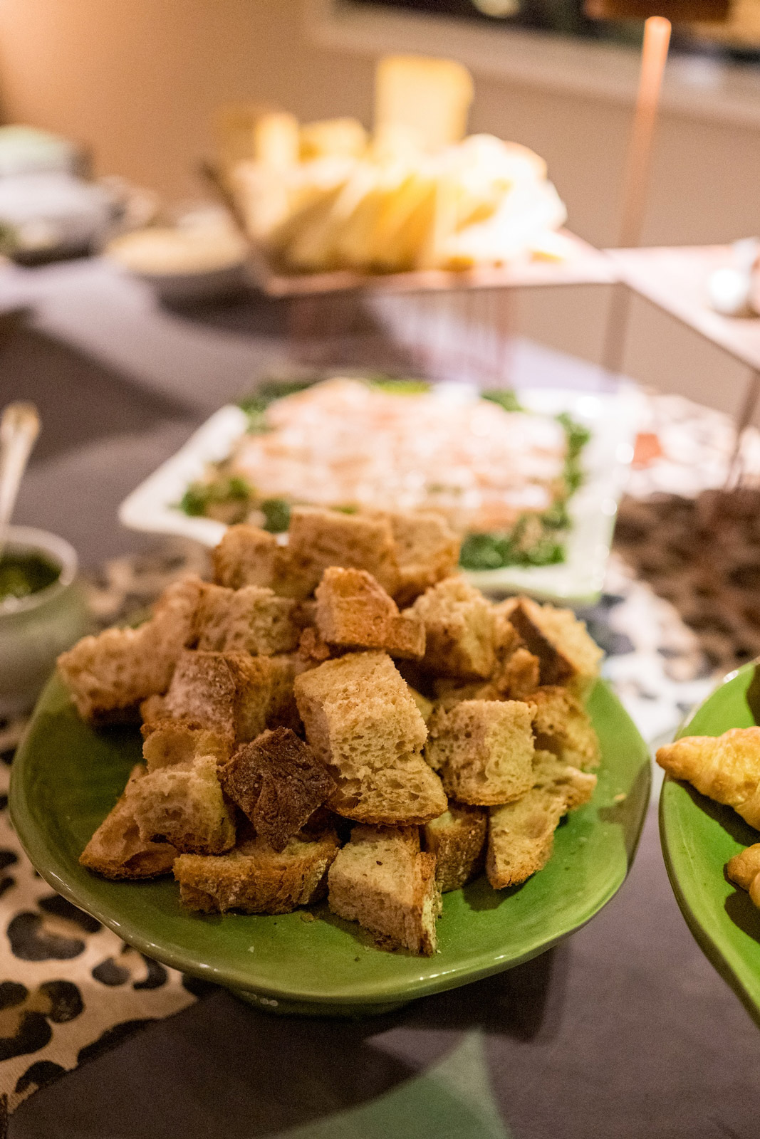 Close-up of bread croutons placed on a green plate and appetizers in the background - ACCAELLE Events | Organizzazione eventi e Wedding planner