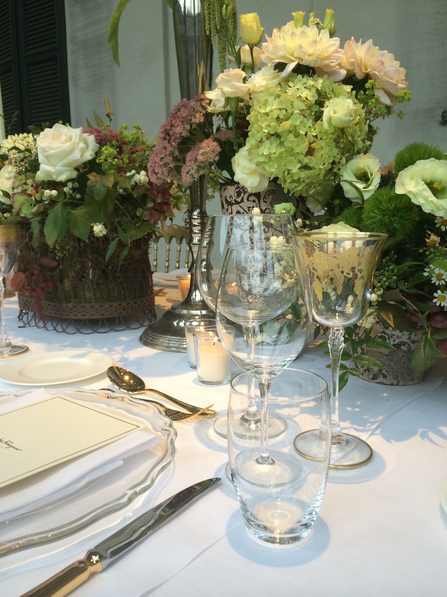 Close-up of crystal glasses and delicate floral arrangements on a white tablecloth. - ACCAELLE Events | Organizzazione eventi e Wedding planner