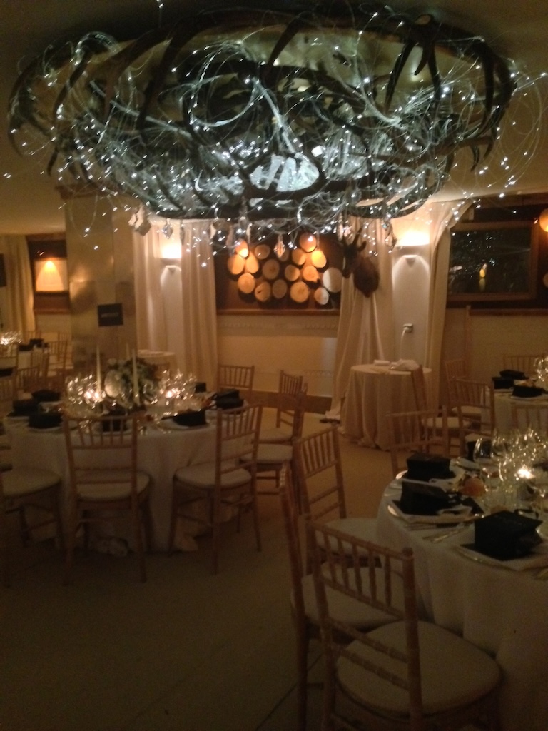 Room with elegantly set tables and a coloured chandelier made of intertwined deer antlers - ACCAELLE Events | Organizzazione eventi e Wedding planner