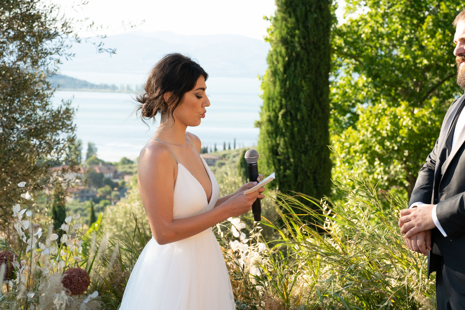 Bride in white dress reading her vows during an outdoor wedding ceremony. - ACCAELLE Events | Organizzazione eventi e Wedding planner