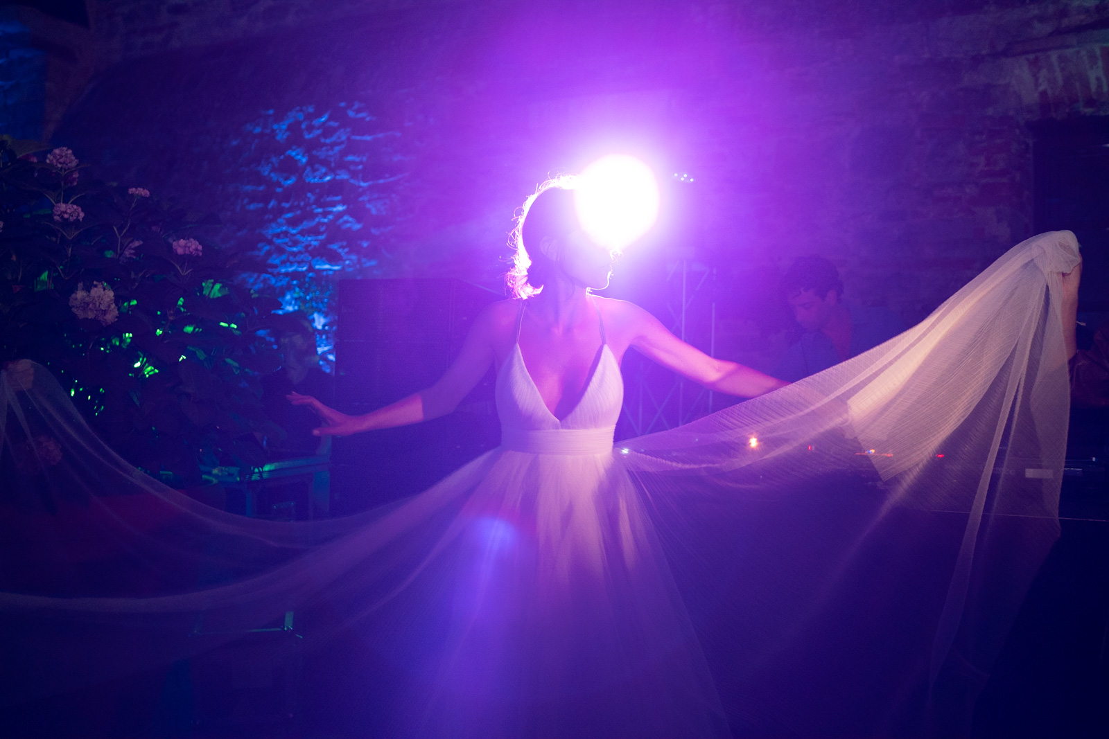 Bride twirling her veil under a play of purple and blue lights. - ACCAELLE Events | Organizzazione eventi e Wedding planner