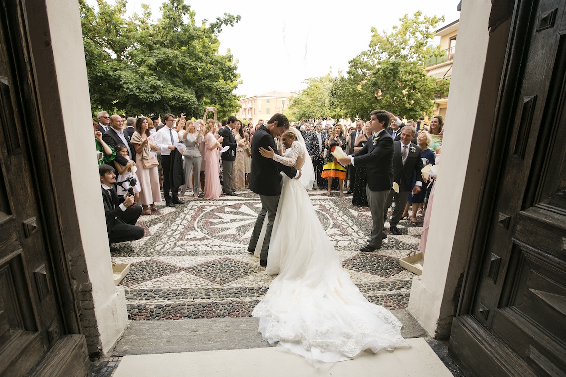 Newlyweds leaving the church surrounded by guests throwing rice - ACCAELLE Events | Organizzazione eventi e Wedding planner