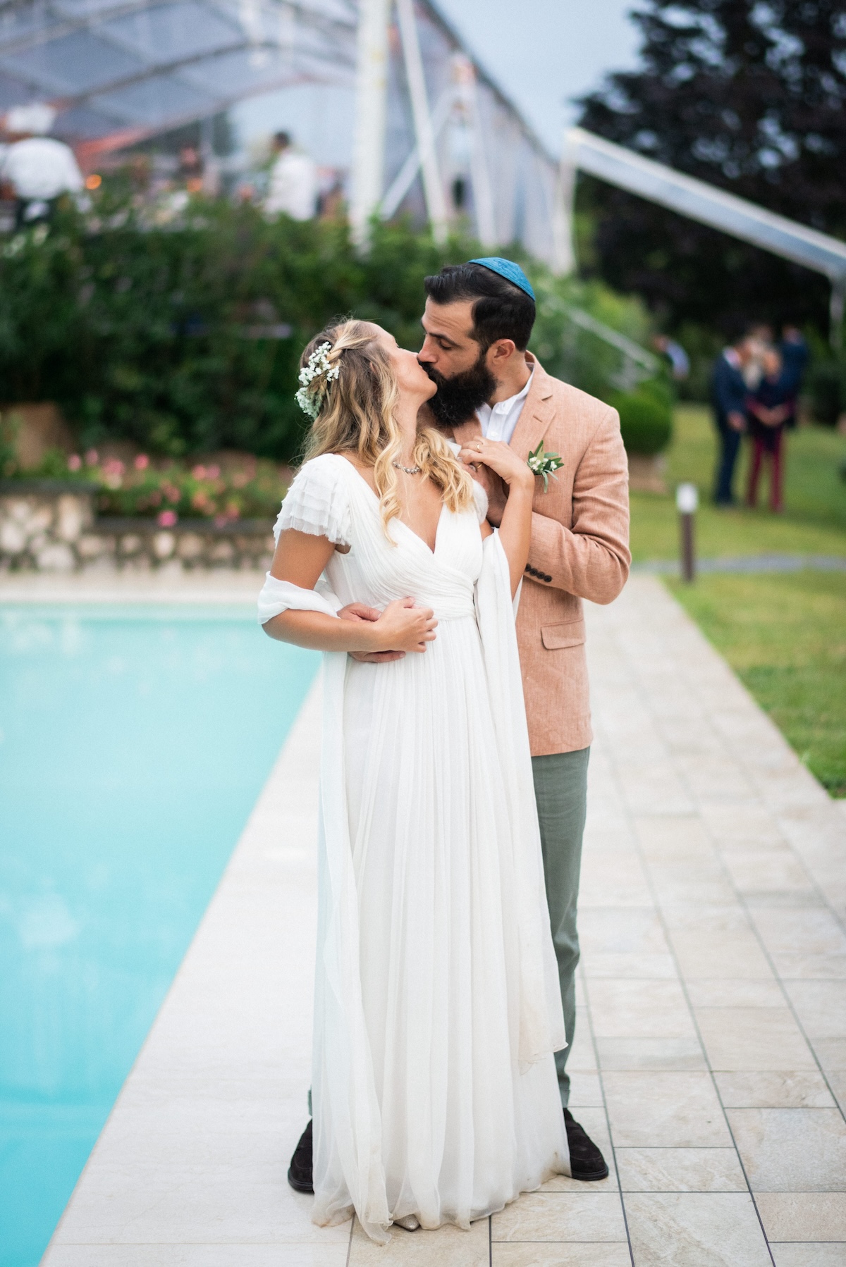 Newlyweds sharing a romantic kiss by the pool in an outdoor location. - ACCAELLE Events | Organizzazione eventi e Wedding planner