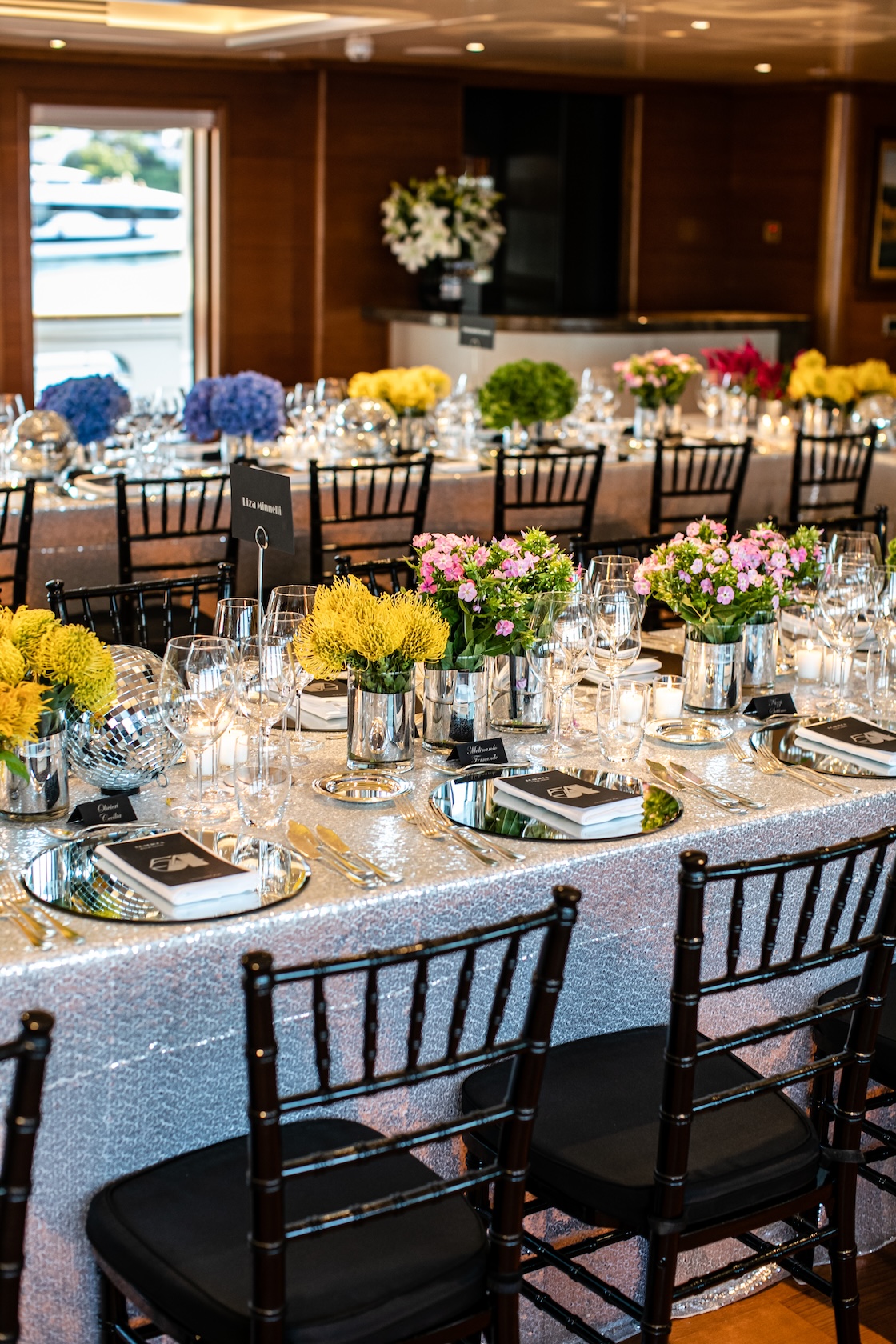 Formal table setting with geometric black chairs inside the saloon of a boat. - ACCAELLE Events | Organizzazione eventi e Wedding planner