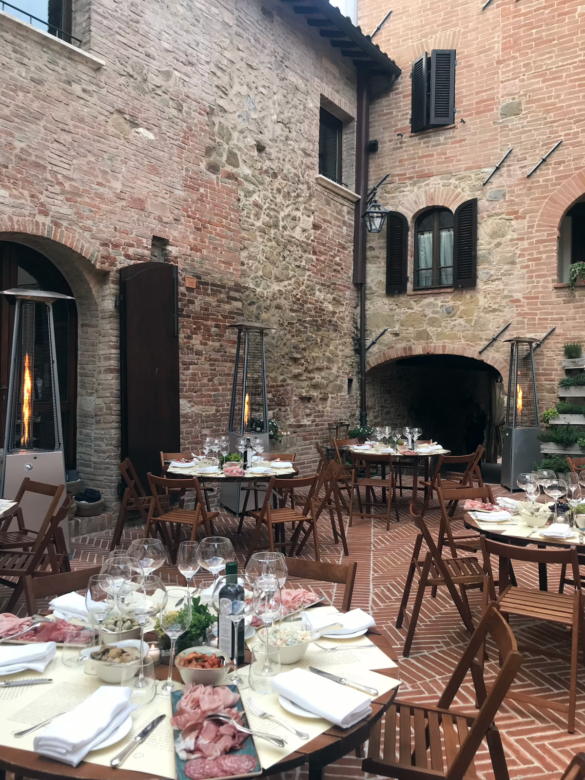 Round tables set up for a reception in the internal courtyard of a medieval castle. - ACCAELLE Events | Organizzazione eventi e Wedding planner