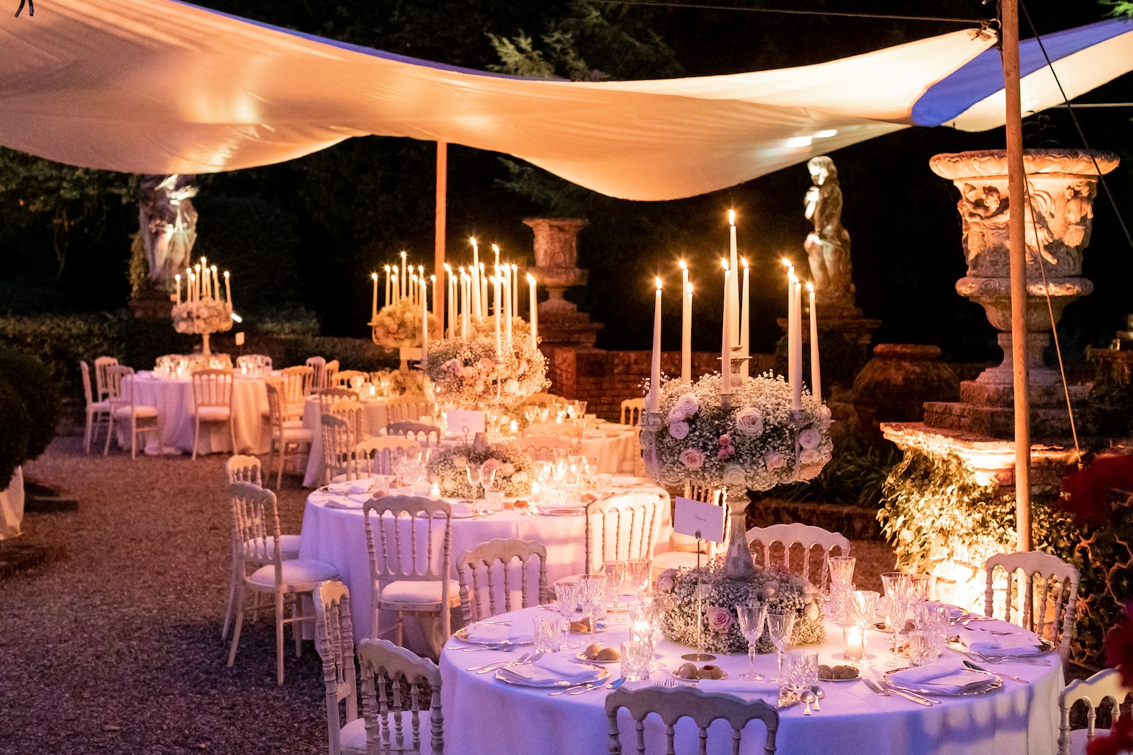 Round gala tables with tall classic candelabras and flowers in soft tones. - ACCAELLE Events | Organizzazione eventi e Wedding planner