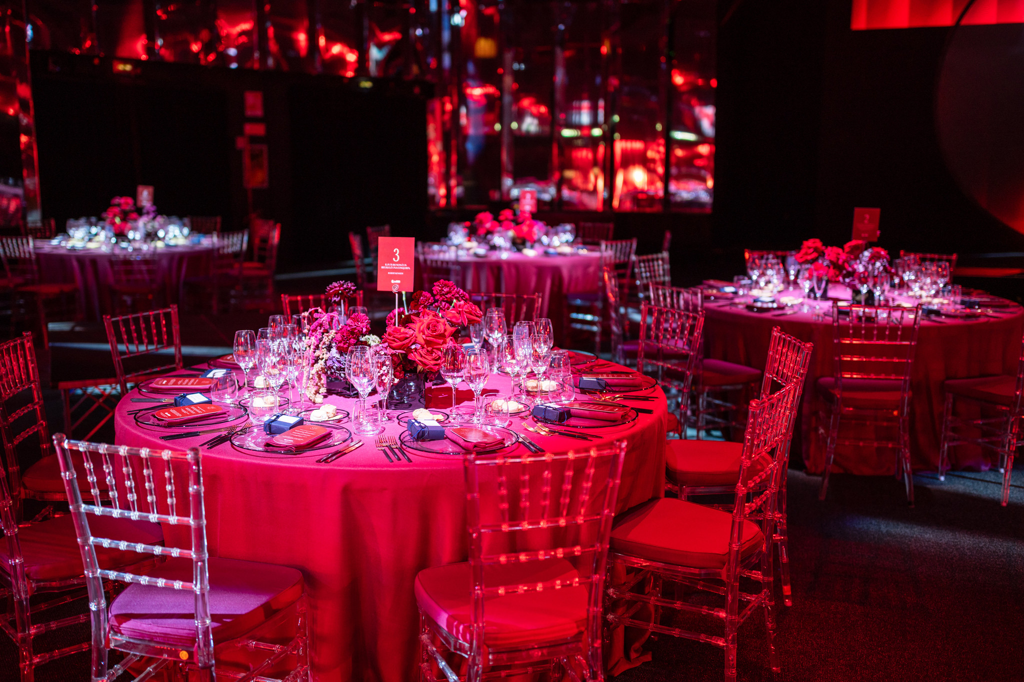 Round tables for a gala dinner bathed in intense red lighting. - ACCAELLE Events | Organizzazione eventi e Wedding planner