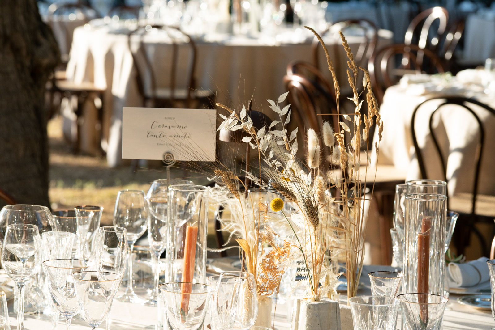 Reception table set up outdoors in the countryside with rustic and floral decorations. - ACCAELLE Events | Organizzazione eventi e Wedding planner