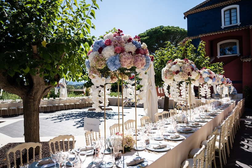 Table decorated for a wedding lunch with a bouquet of multicolored flowers placed on top and trees in the background - ACCAELLE Events | Organizzazione eventi e Wedding planner