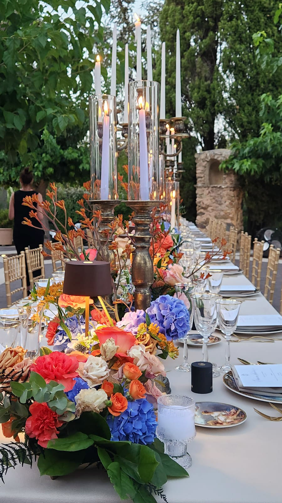 Imperial outdoor table with multicolored flowers and a large crystal candelabra. - ACCAELLE Events | Organizzazione eventi e Wedding planner