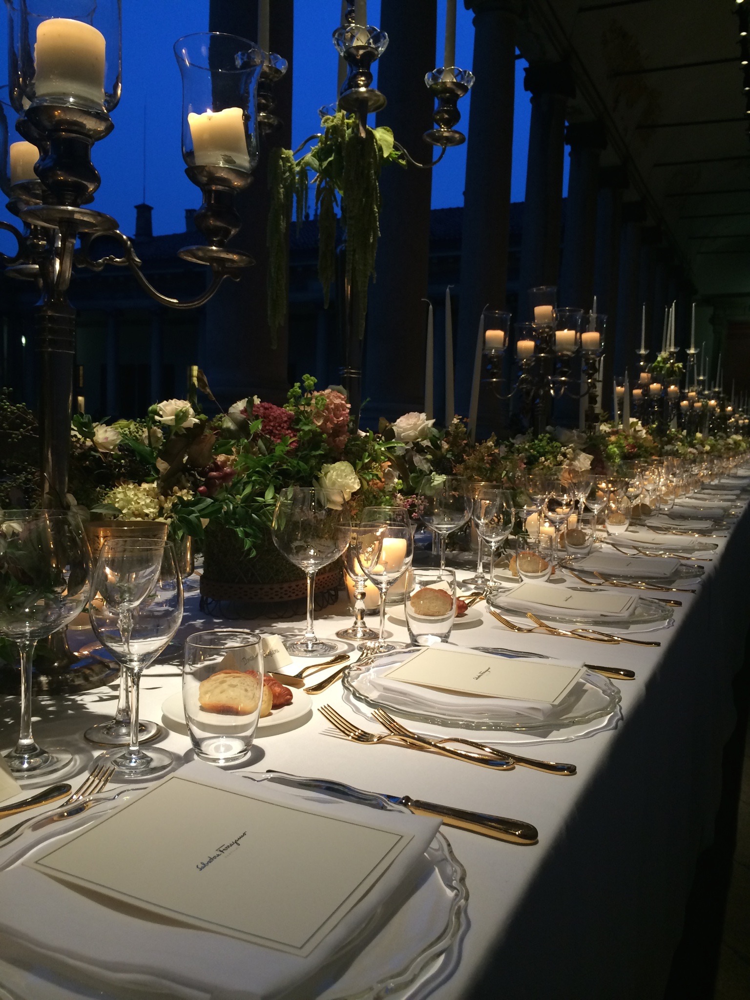 Imperial table in the evening with tall candelabras and warm lights illuminating the porch. - ACCAELLE Events | Organizzazione eventi e Wedding planner
