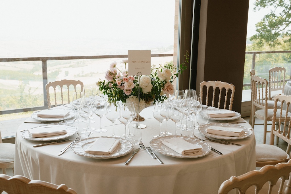 Elegantly set round table with a bouquet of white and pink roses placed in the center - ACCAELLE Events | Organizzazione eventi e Wedding planner