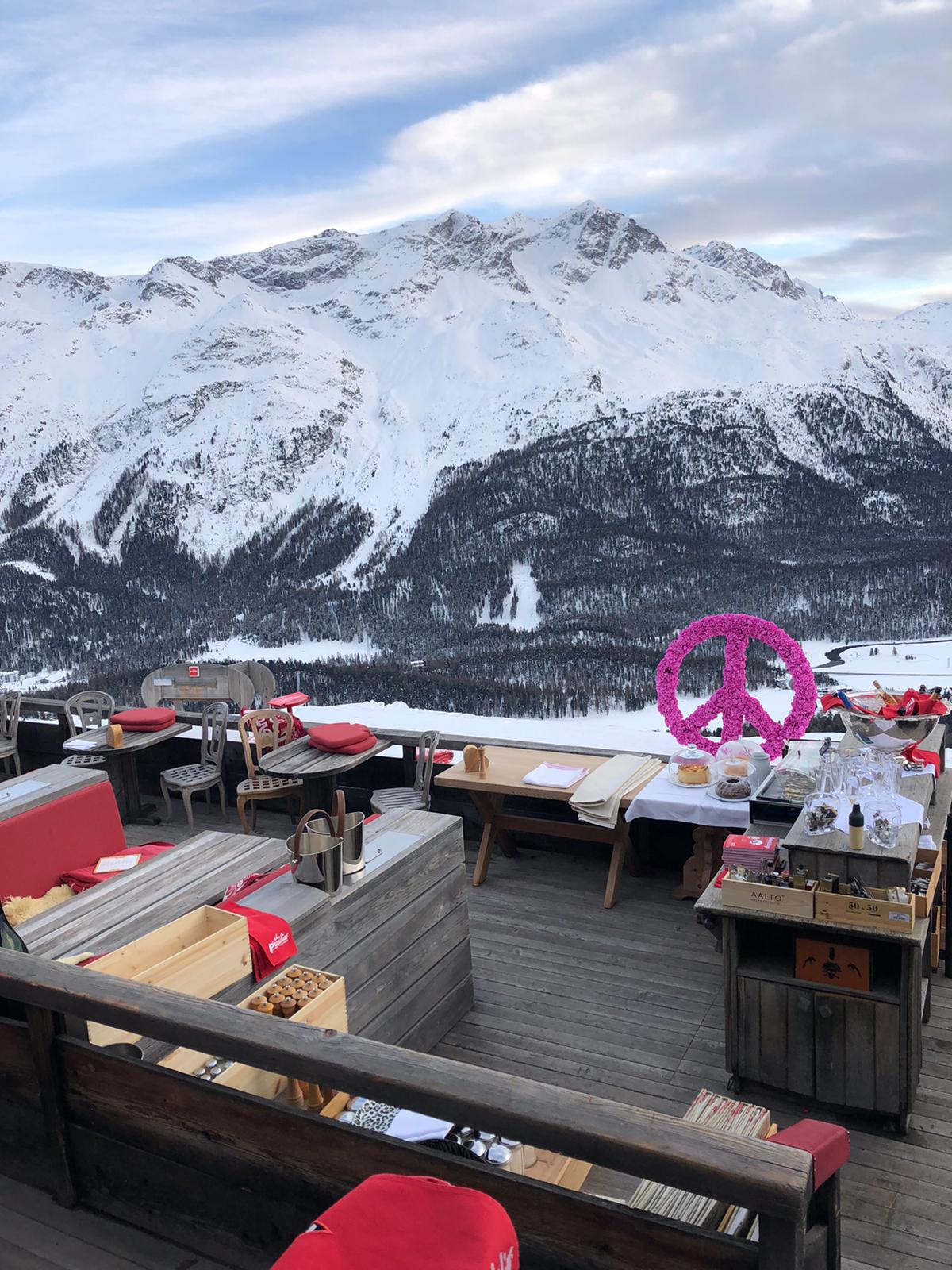 Panoramic terrace set up for an exclusive mountain event, with seating, blankets and snow-capped mountains in the background - ACCAELLE Events | Organizzazione eventi e Wedding planner