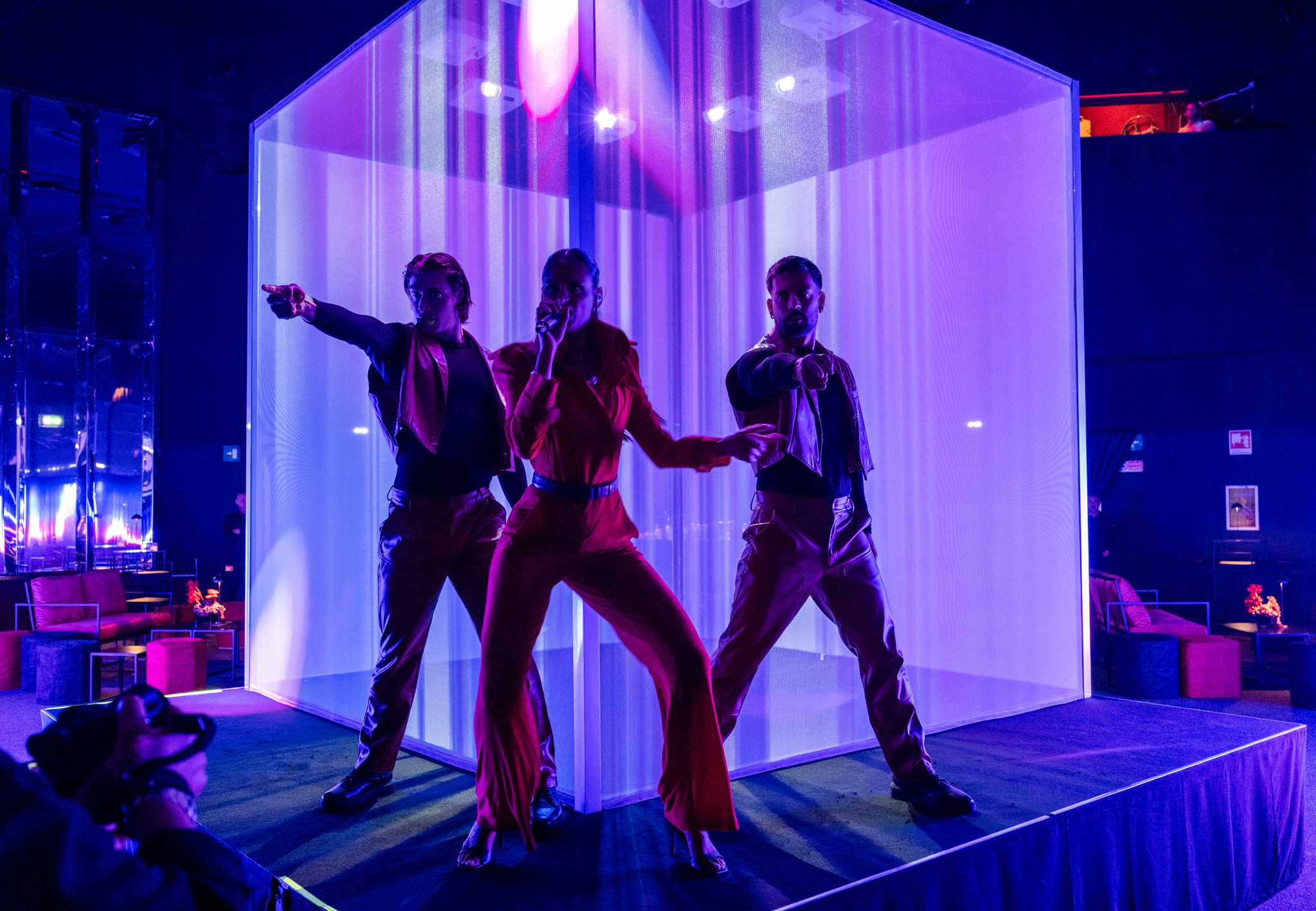 Three dancers perform in front of a large cubic structure illuminated in purple. - ACCAELLE Events | Organizzazione eventi e Wedding planner