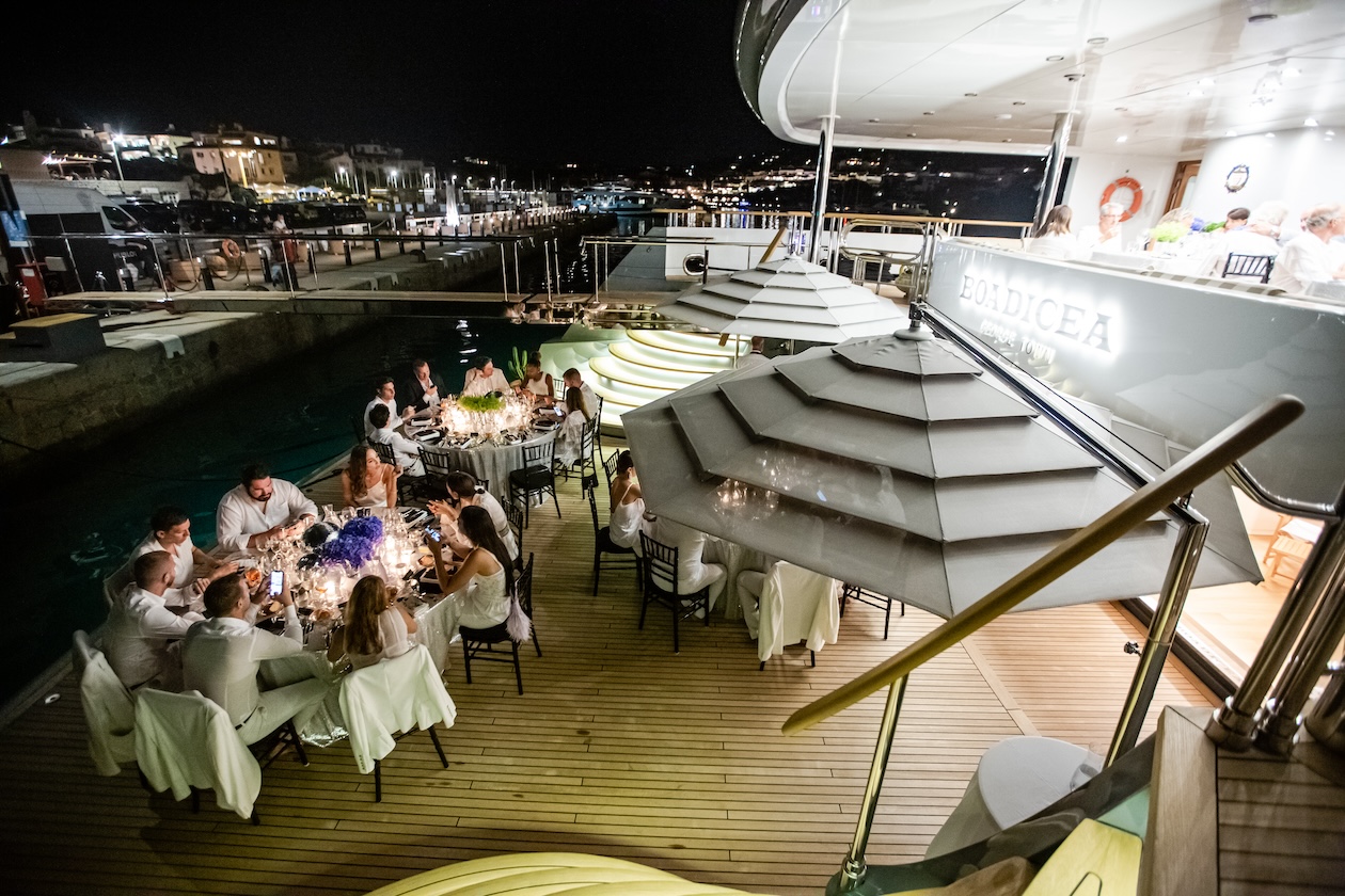 Top view of guests sitting at tables on a luxury yacht in the evening - ACCAELLE Events | Organizzazione eventi e Wedding planner